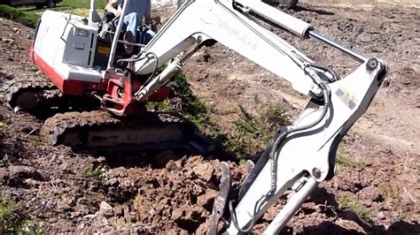 mini excavator trenching across a slope|excavation on a hill.